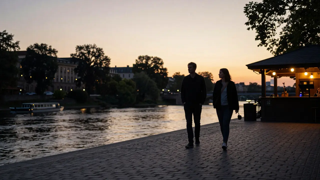 Two individuals walking peacefully along the Spree River at sunset, lost in quiet companionship.